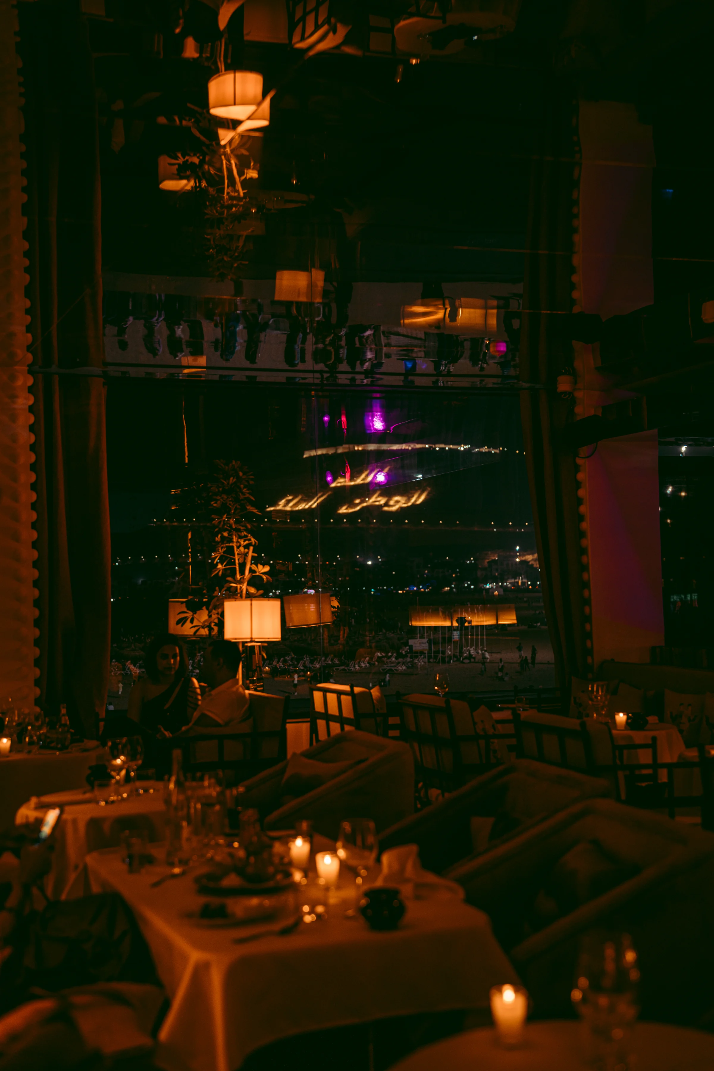 Candlelit Rooftop tables reflected in glass at night