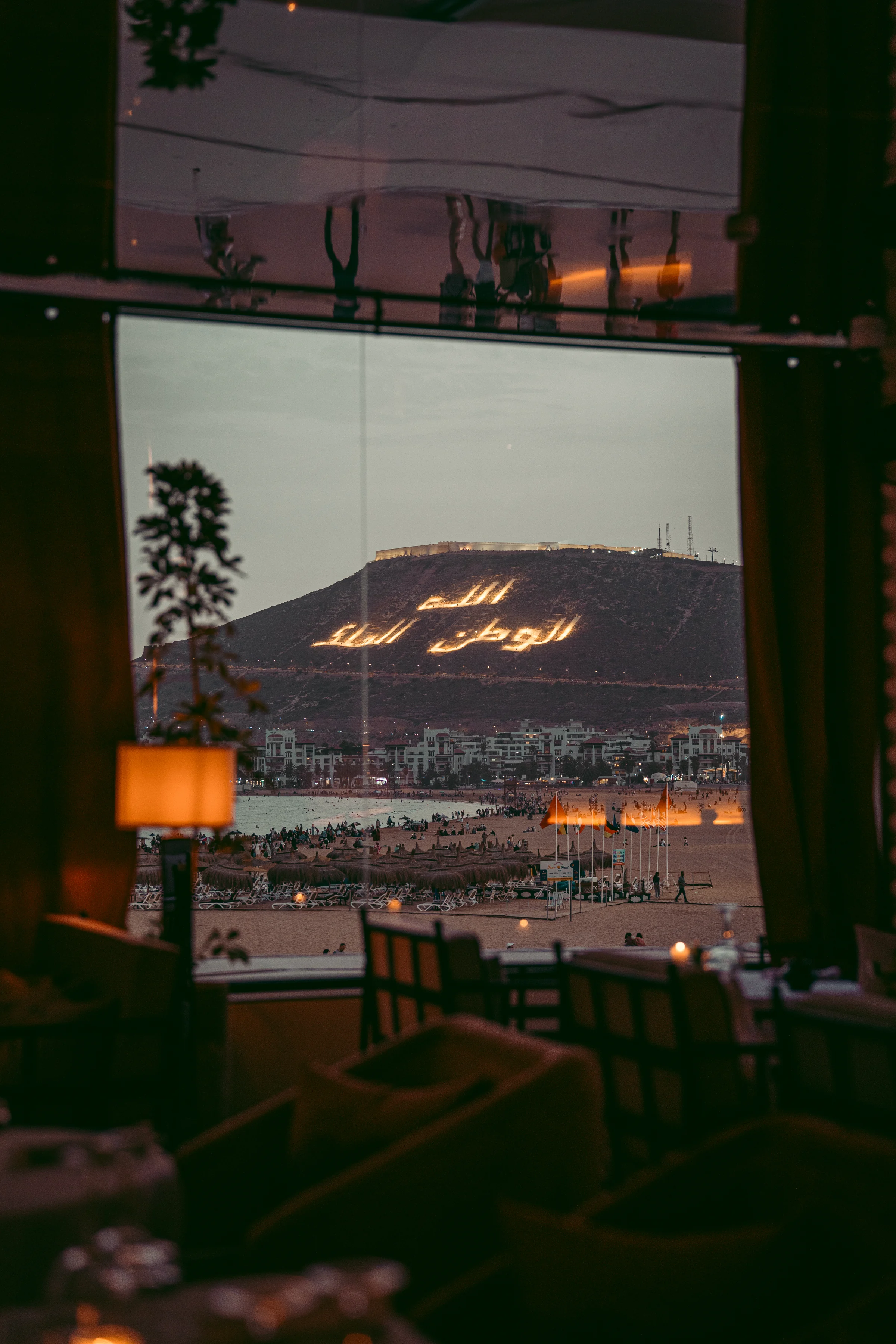 The illuminated Agadir Oufella hillside framed by Rooftop tables at night