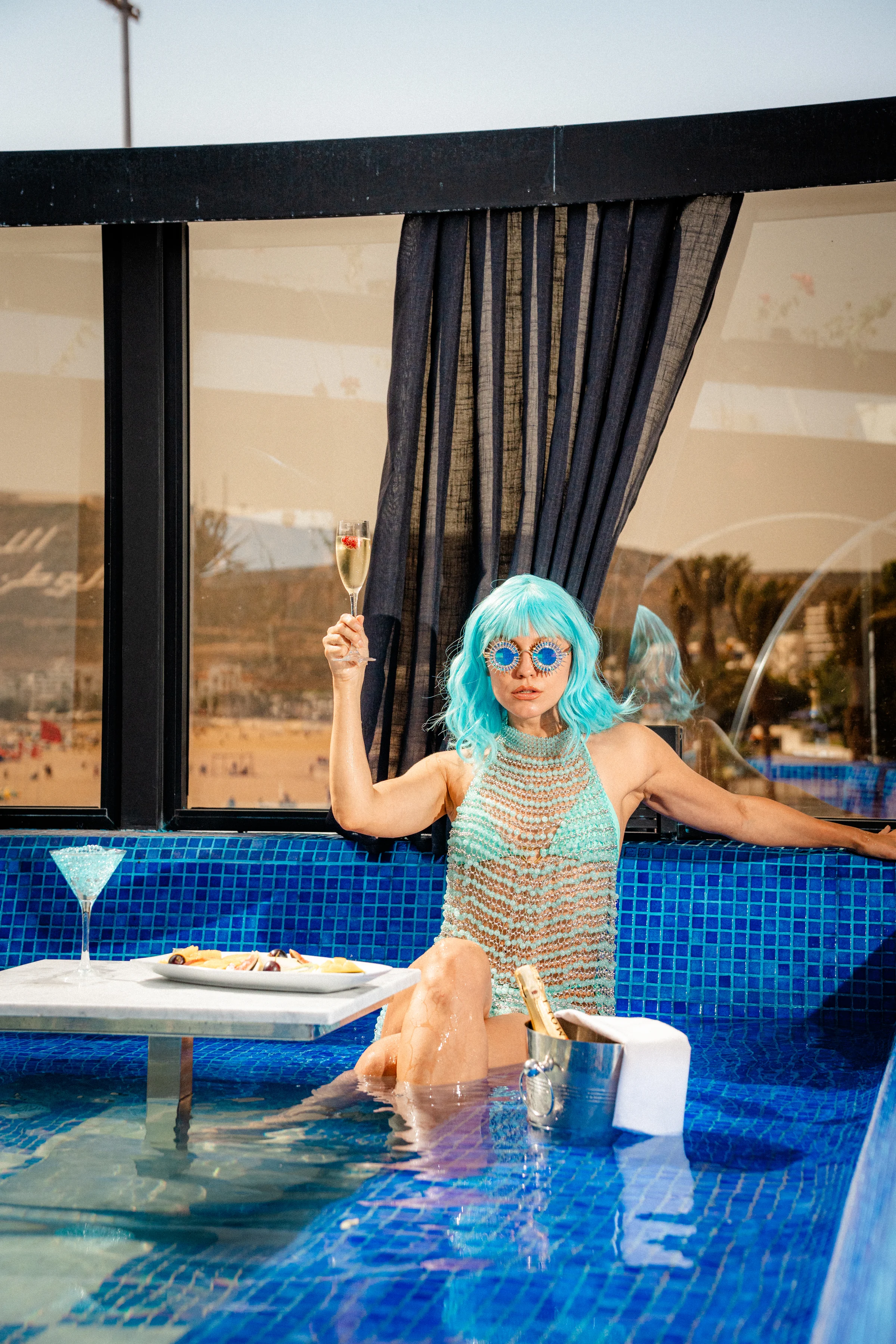 Guest raising a glass while seated in the blue Rooftop pool