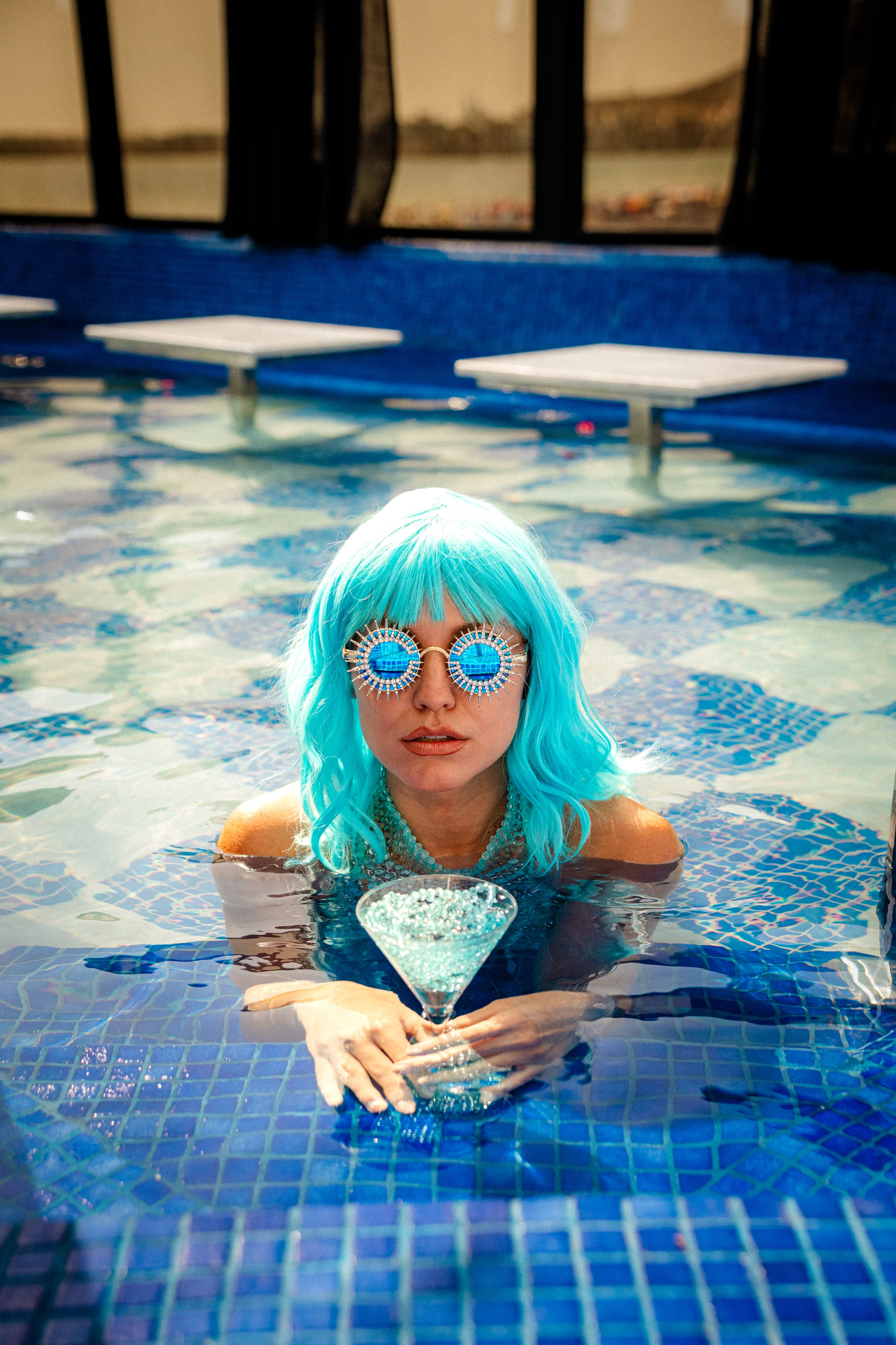 Guest holding a blue cocktail while relaxing in the Rooftop pool
