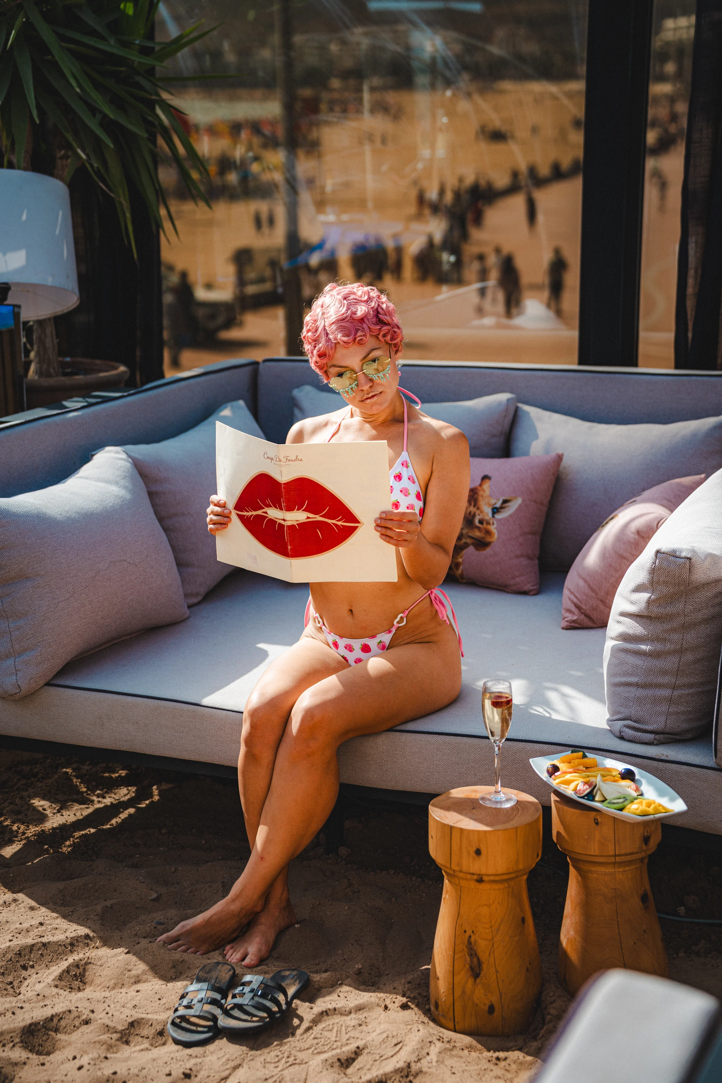 Guest reading the Coup de Foudre menu on a sunlit Rooftop sofa